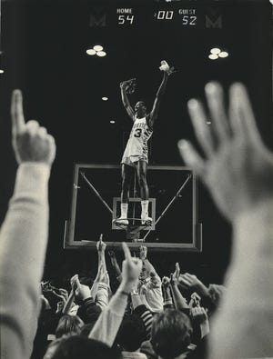 Marquette player Michael Wilson celebrates on top of the rim at the MECCA after MU beat Notre Dame, 54-52, in 1981 on a last-second shot from Glenn "Doc" Rivers.