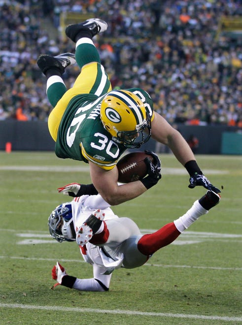 Green Bay Packers fullback John Kuhn (30) dives over New York Giants cornerback Aaron Ross during an 8-yard touchdown reception in the first the first half of an NFL divisional playoff football game Sunday, Jan. 15, 2012, in Green Bay, Wis.