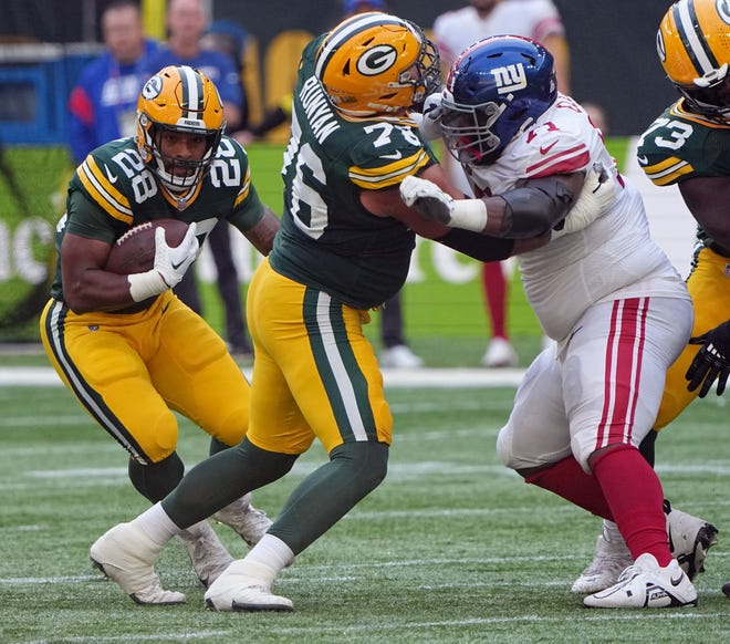 Green Bay Packers running back AJ Dillon (28) runs with the ball around a block by guard Jon Runyan (76) against New York Giants defensive tackle Justin Ellis (71) during the first quarter at Tottenham Hotspur Stadium. The New York Giants beat the Green Bay Packers 27-22.