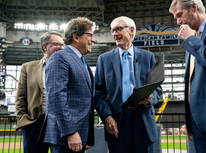 Gov. Tony Evers shows Milwaukee Brewers owner (center) Mark Attanasio Assembly Bill 438 and Assembly Bill 439, a bipartisan package of bills passed by the Wisconsin State Legislature to keep the Milwaukee Brewers and Major League Baseball (MLB) in Wisconsin through 2050, on Tuesday December 5, 2023 at American Family Field in Milwaukee, Wis.