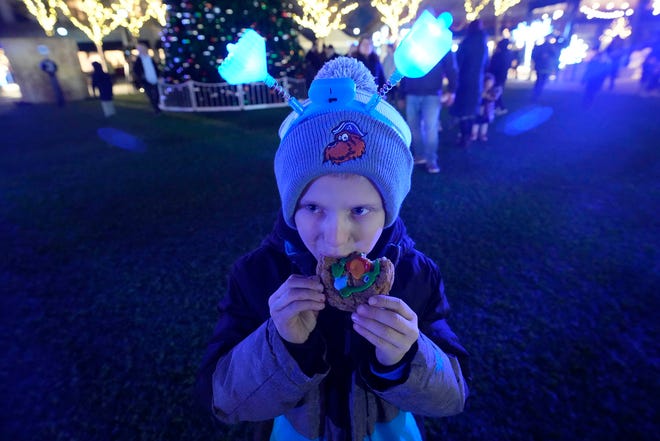 Natan Rogovskiy, of Whitefish Bay, who was with his mother, Nadiia, eats a cookie he decorated as part of a Chanukah Festival and Gelt Drop, to kick off the first day of Chanukah, in The Yard at Bayshore in Glendale on Thursday, Dec. 7, 2023. The largest Hanukkah festival in Wisconsin, hosted by Lubavitch of Wisconsin, included live music, a giant Menorah lighting, and a mega gelt and gift drop.