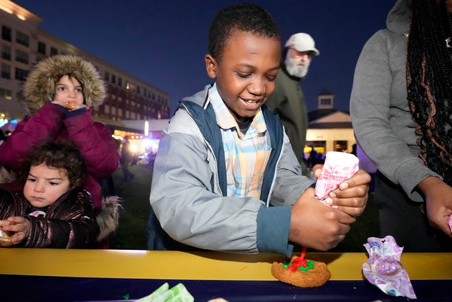 Eljack Murrell, celebrating his 9th birthday with his sister and father, Eljack Murrell, Sr. (not pictured) of Milwaukee, decorates a cookie as part of a Chanukah Festival and Gelt Drop, to kick off the first day of Chanukah, in The Yard at Bayshore in Glendale on Thursday, Dec. 7, 2023. The largest Hanukkah festival in Wisconsin, hosted by Lubavitch of Wisconsin, included live music, a giant Menorah lighting, and a mega gelt and gift drop.