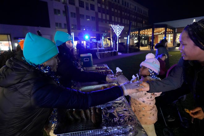 A group of students with Bader Hillel High School in Glendale serve doughnuts as part of a Chanukah Festival and Gelt Drop, to kick off the first day of Chanukah, in The Yard at Bayshore in Glendale on Thursday, Dec. 7, 2023. The largest Hanukkah festival in Wisconsin, hosted by Lubavitch of Wisconsin, included live music, a giant Menorah lighting, and a mega gelt and gift drop.