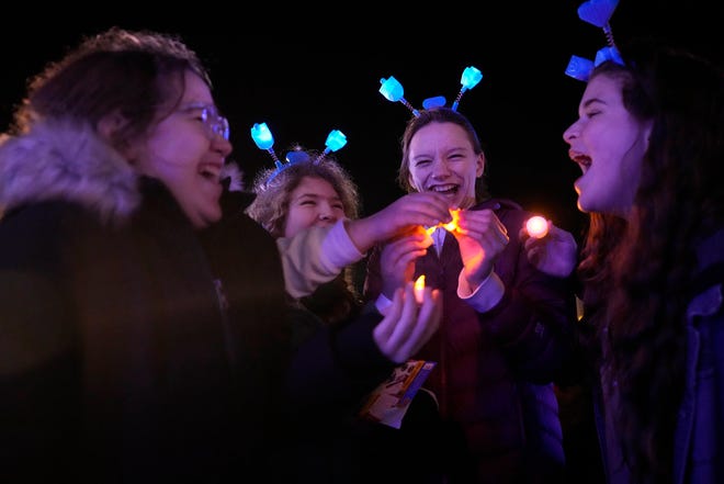 A group dance with their votive candles handed out as part of a Chanukah Festival and Gelt Drop, to kick off the first day of Chanukah, in The Yard at Bayshore in Glendale on Thursday, Dec. 7, 2023. The largest Hanukkah festival in Wisconsin, hosted by Lubavitch of Wisconsin, included live music, a giant Menorah lighting, and a mega gelt and gift drop.