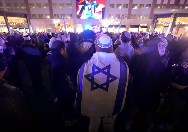 Yasha Moldavsky, a Bader Hillel High School junior, wears a flag of Israel during a Chanukah Festival and Gelt Drop, to kick off the first day of Chanukah, in The Yard at Bayshore in Glendale on Thursday, Dec. 7, 2023. The largest Hanukkah festival in Wisconsin, hosted by Lubavitch of Wisconsin, included live music, a giant Menorah lighting, and a mega gelt and gift drop.