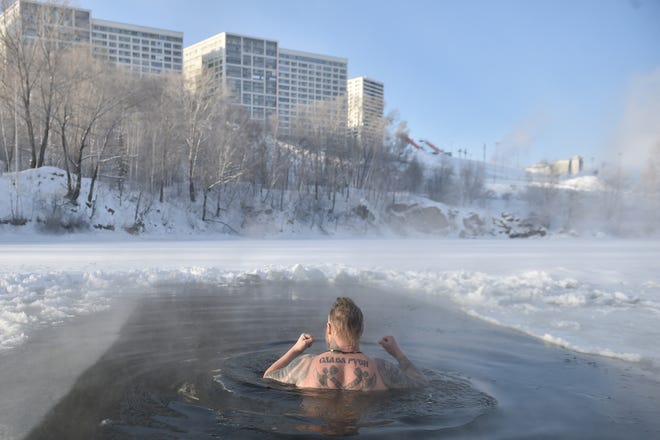 December 9, 2023: A winter swimming enthusiast swims in an ice hole at a lake in the Siberian city of Novosibirsk, with the air temperature around minus 35 degrees Celsius. The tattoo reads "Glory to the Rus (referring to Russia)".