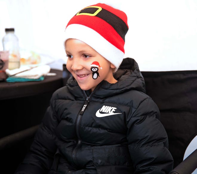 Norman Harris, 6, gets a penguin painted on his face during the Cocoa with the Clauses event in Cathedral Square Park in Milwaukee, Wis. on Saturday, Dec. 9, 2023.