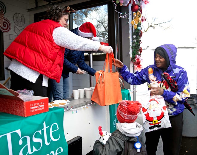 Beth Tomkiw hands out a bag of free cooking supplies to an event attendee of the Cocoa with the Clauses event in Cathedral Square Park in Milwaukee, Wis. on Saturday, Dec. 9, 2023.