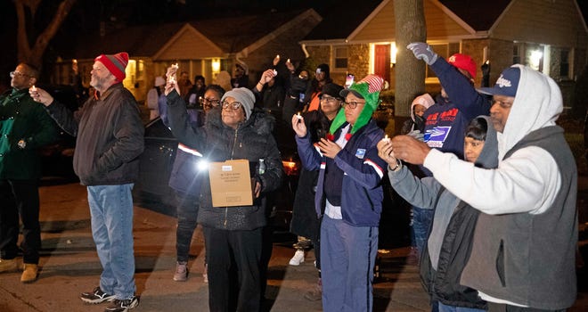 Community members raise candles in the air during a vigil on Dec. 9, 2023 honoring the life of Aundre Cross, a 44-year-old U.S. Postal Service worker who was shot and killed while delivering mail a year ago on Dec. 9, 2022 in the 5000 block of North 65th Street in Milwaukee.