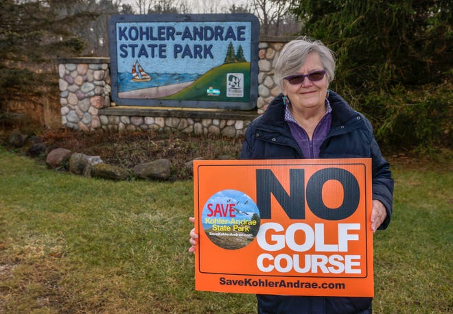 Mary Faydash holds a sign against the proposed Kohler Golf course near Kohler-Andrae State Park, Tuesday, December 14, 2021, in Sheboygan, Wis. Faydash is part of a group that is opposed to Kohler Company building a golf course adjacent to the park.